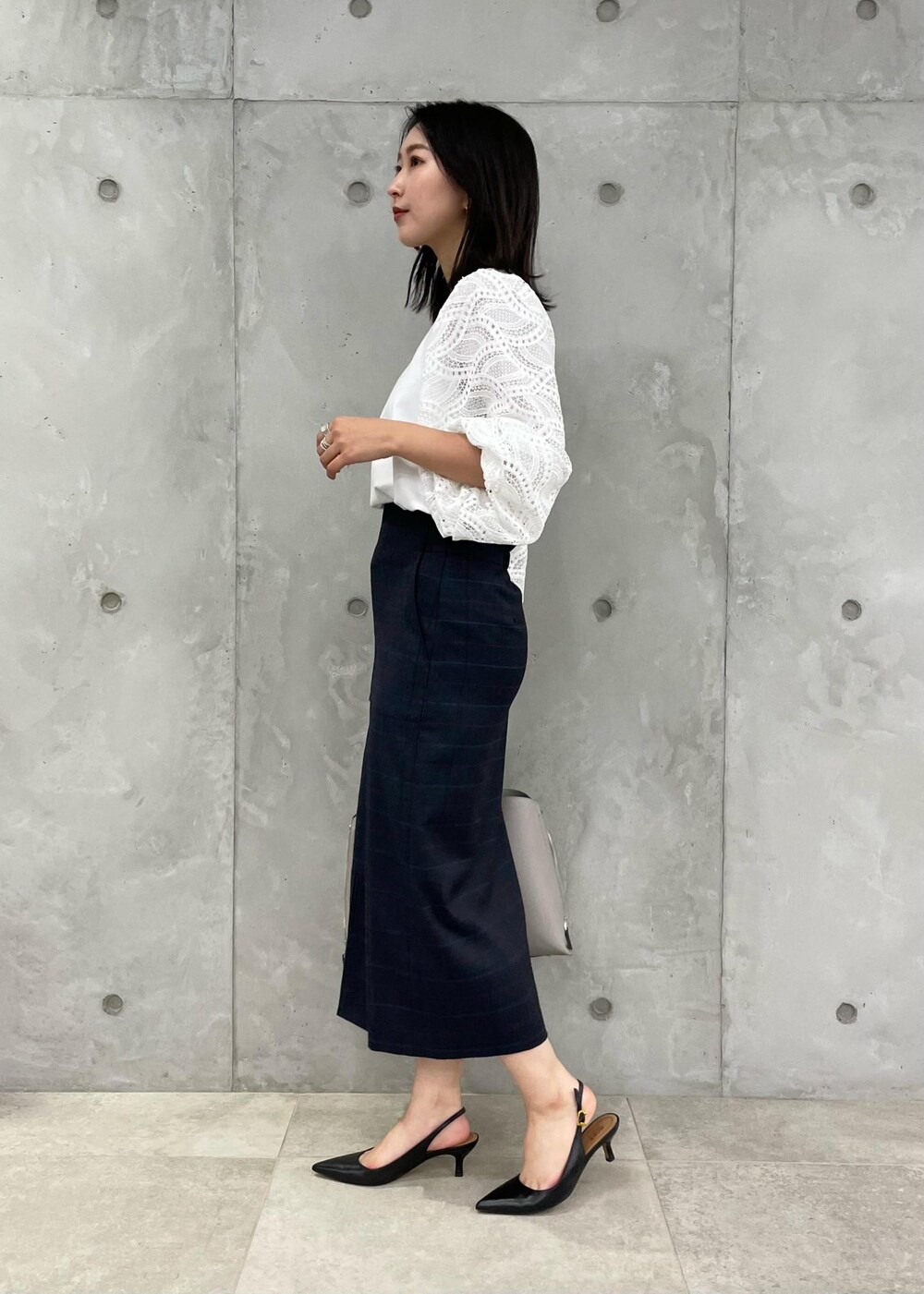 ブラック系のパンプス、グレー系のトートバッグ、ブルー系のスカートを着用したレディースの秋コーディネートの4枚目の写真