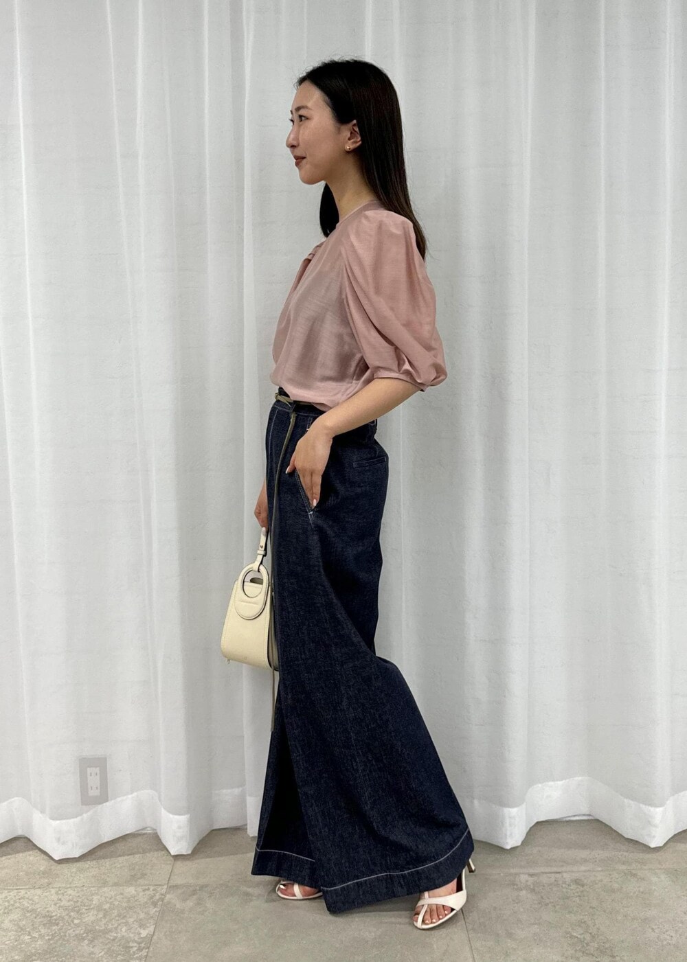 ホワイト系のハンドバッグ、ブルー系のデニムパンツ、ホワイト系のサンダルを着用したレディースの春コーディネートの4枚目の写真