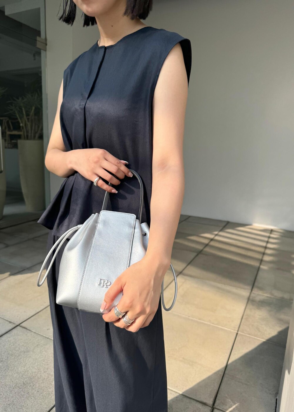 シルバー系のサンダル、シルバー系のハンドバッグ、ブルー系のシャツ/ブラウスを着用したレディースの夏コーディネートの10枚目の写真