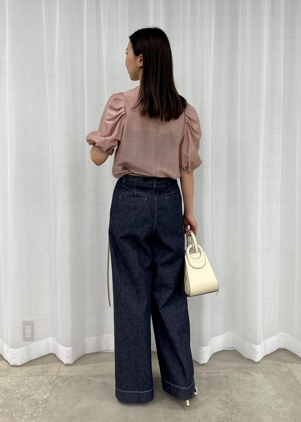 ホワイト系のハンドバッグ、ブルー系のデニムパンツ、ホワイト系のサンダルを着用したレディースの春コーディネートの3枚目の写真