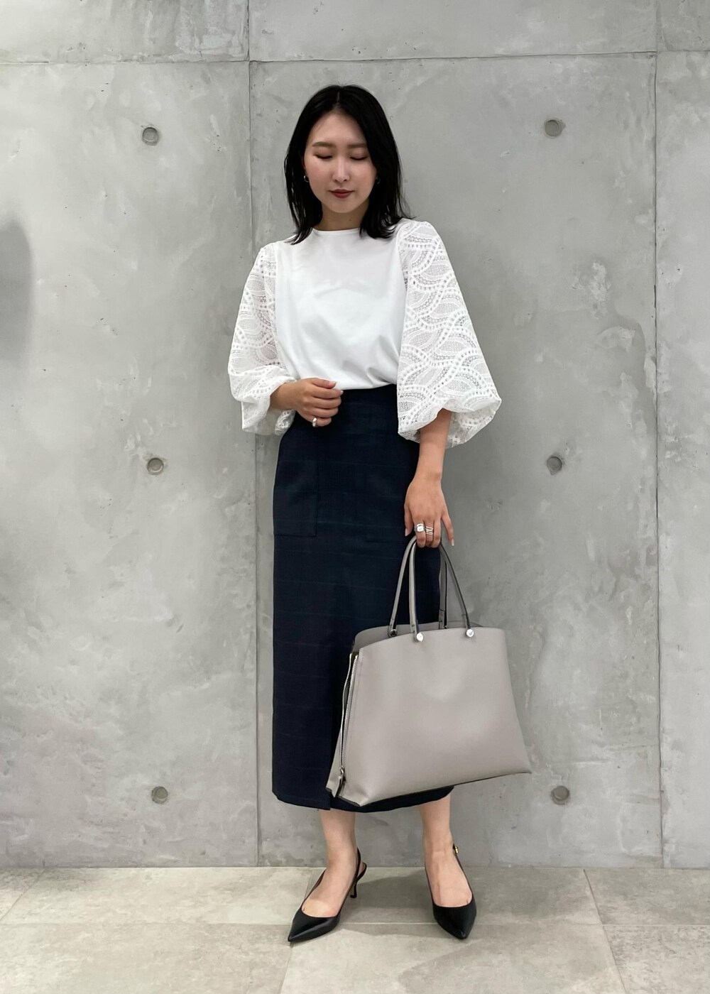 ブラック系のパンプス、グレー系のトートバッグ、ブルー系のスカートを着用したレディースの秋コーディネートの9枚目の写真