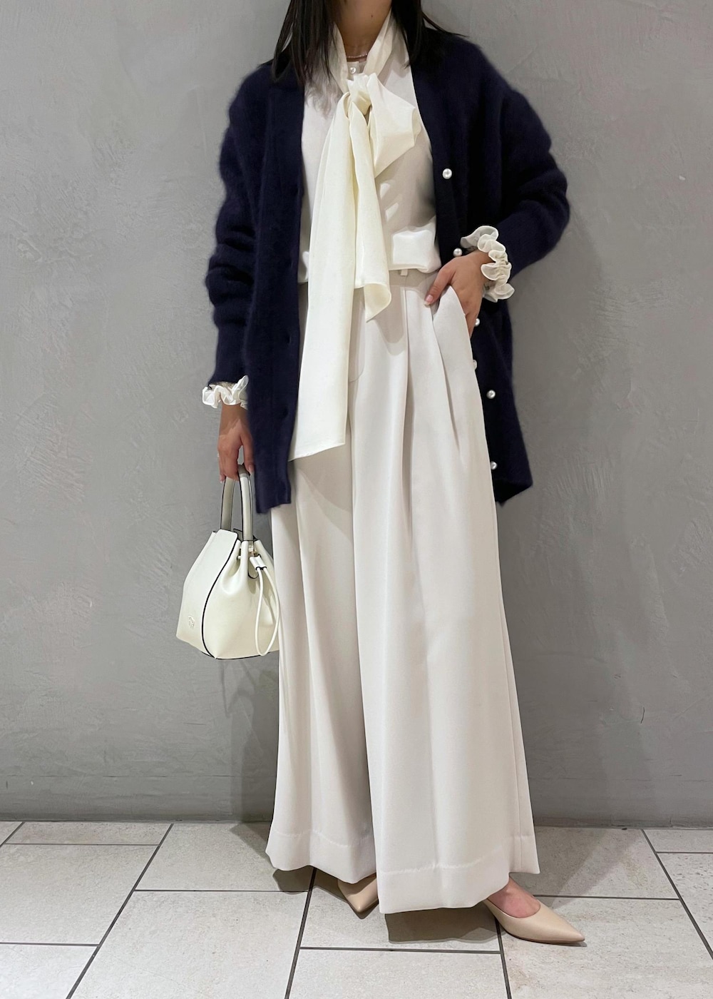 ホワイト系のハンドバッグ、ベージュ系のパンプス、ブルー系のカーディガン/ボレロを着用したレディースの冬コーディネートの9枚目の写真