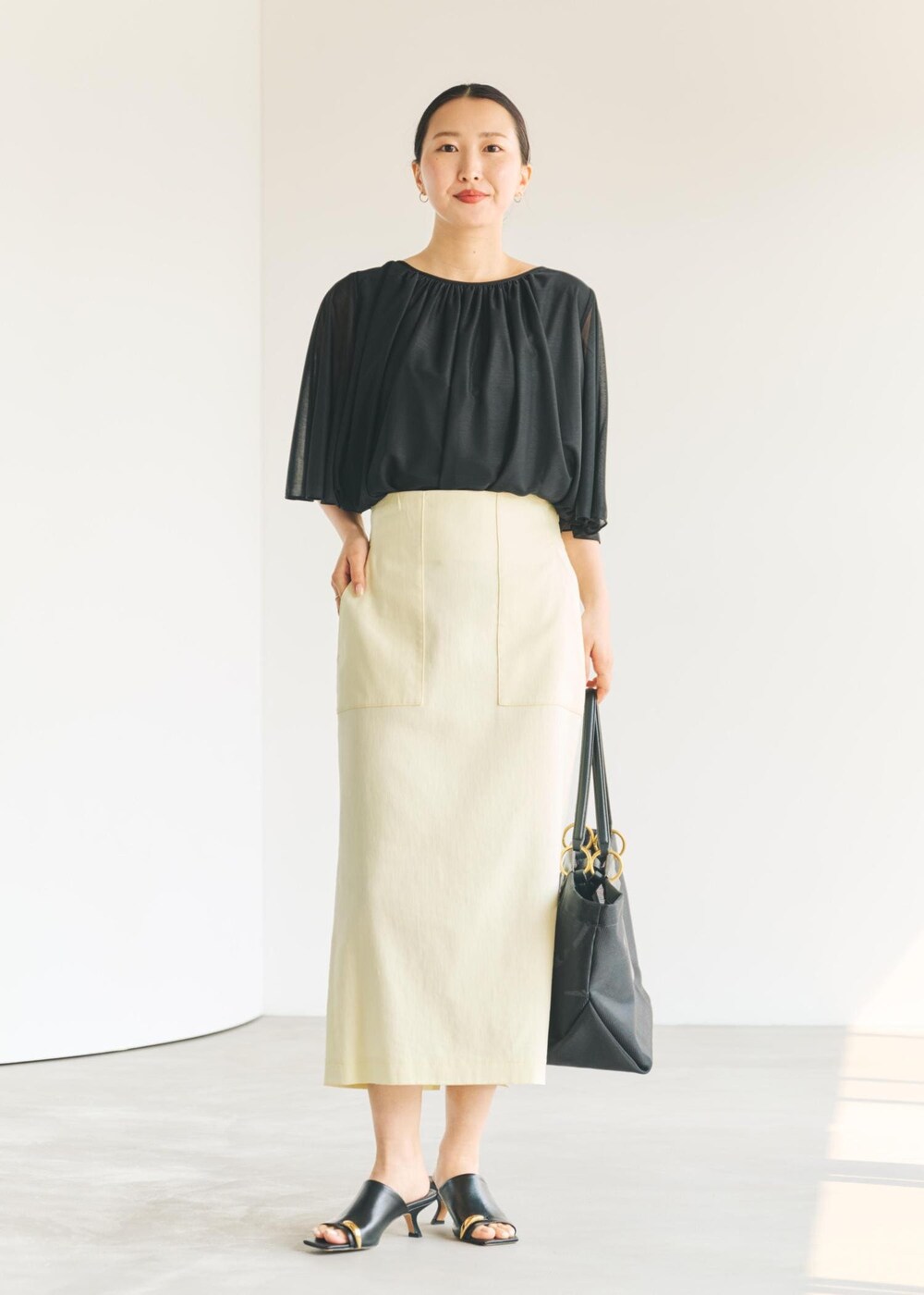 ブラック系のサンダル、ブラック系のトートバッグ、イエロー系のスカートを着用したレディースの春コーディネートの8枚目の写真