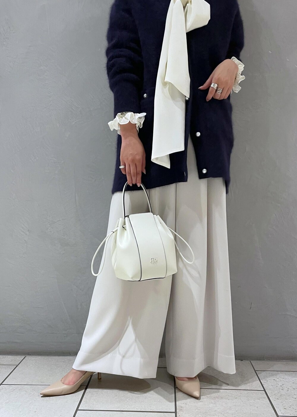 ホワイト系のハンドバッグ、ベージュ系のパンプス、ブルー系のカーディガン/ボレロを着用したレディースの冬コーディネートの10枚目の写真