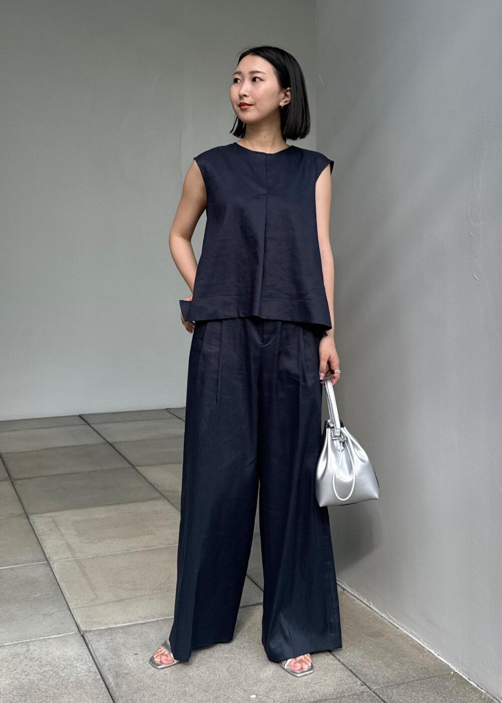 シルバー系のサンダル、シルバー系のハンドバッグ、ブルー系のシャツ/ブラウスを着用したレディースの夏コーディネートの4枚目の写真