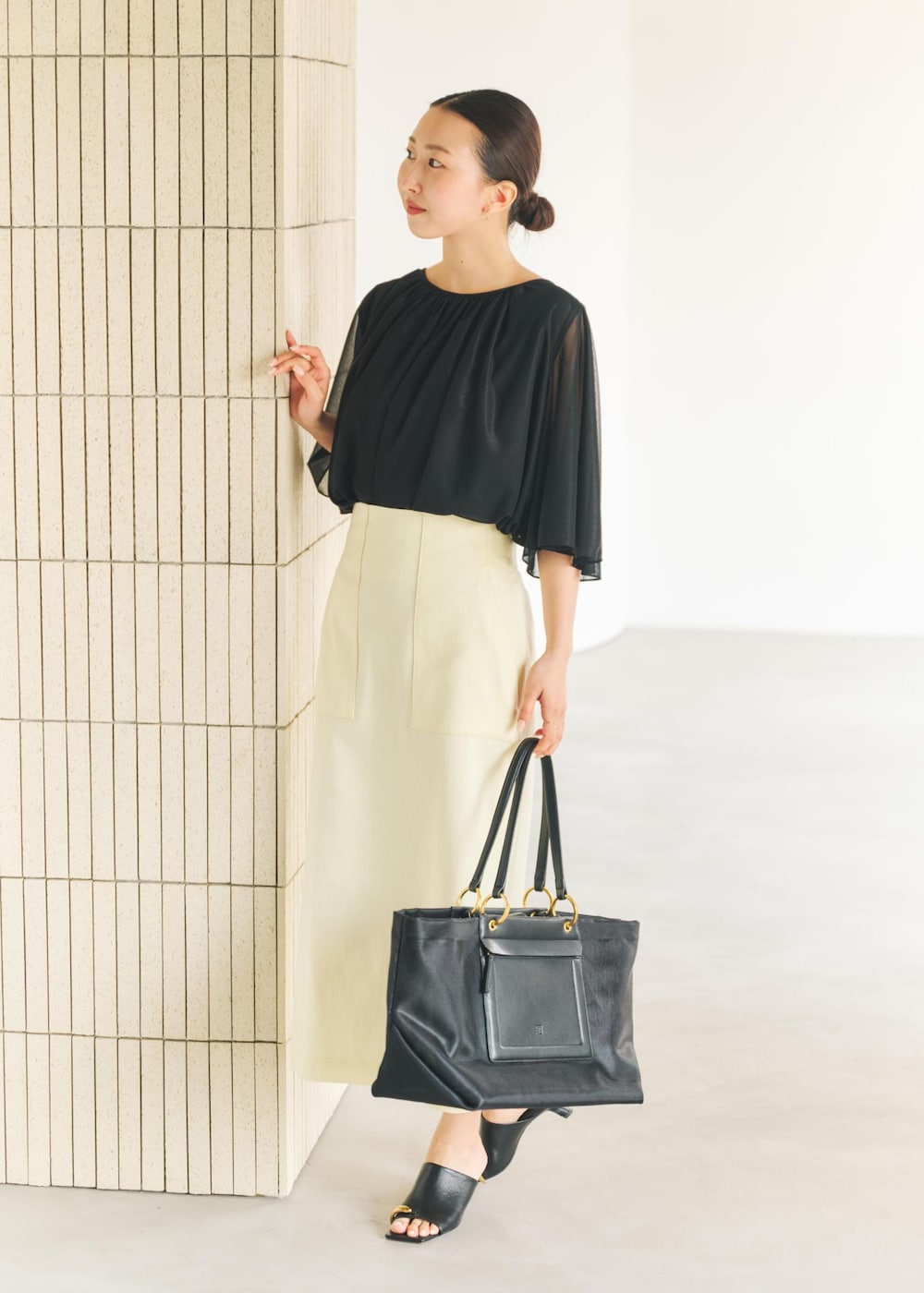 ブラック系のサンダル、ブラック系のトートバッグ、イエロー系のスカートを着用したレディースの春コーディネートの2枚目の写真