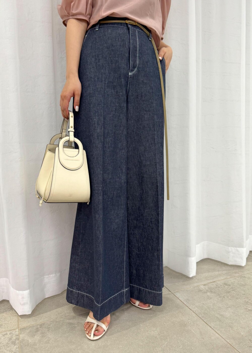 ホワイト系のハンドバッグ、ブルー系のデニムパンツ、ホワイト系のサンダルを着用したレディースの春コーディネートの8枚目の写真