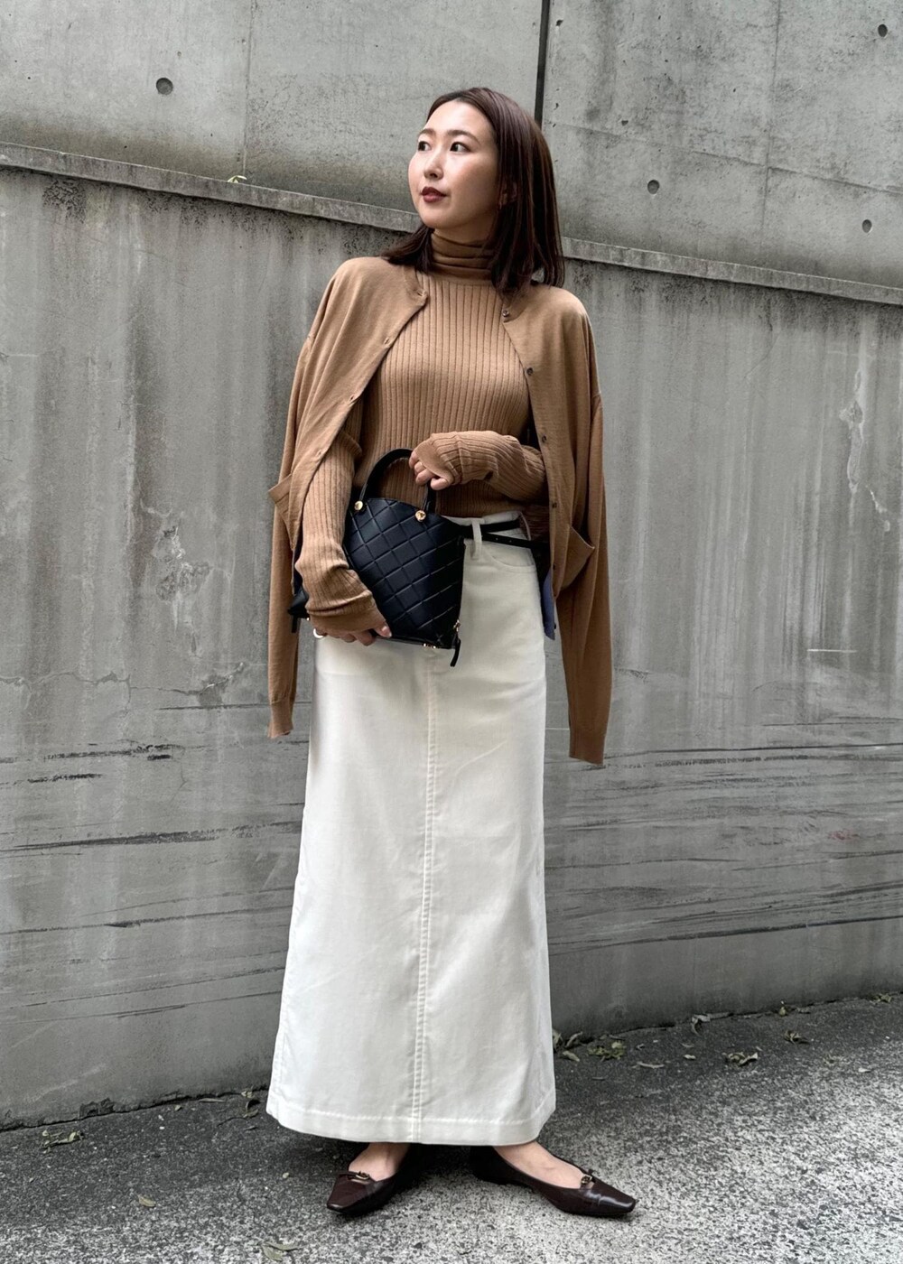 ブラウン系のパンプス、ブラック系のハンドバッグ、ホワイト系のスカートを着用したレディースの冬コーディネートの9枚目の写真