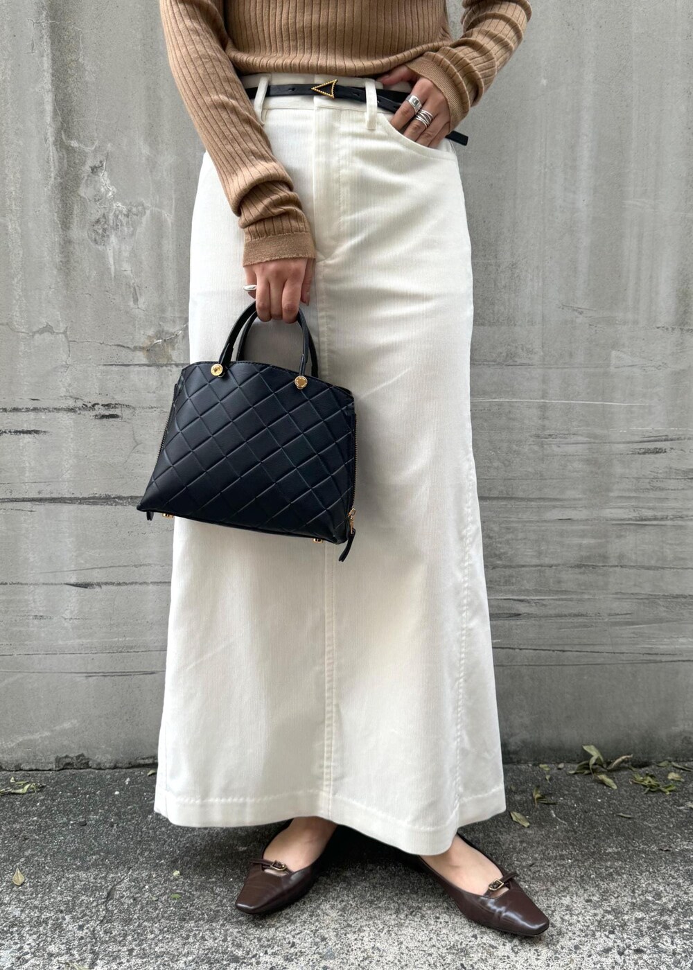 ブラウン系のパンプス、ブラック系のハンドバッグ、ホワイト系のスカートを着用したレディースの冬コーディネートの8枚目の写真