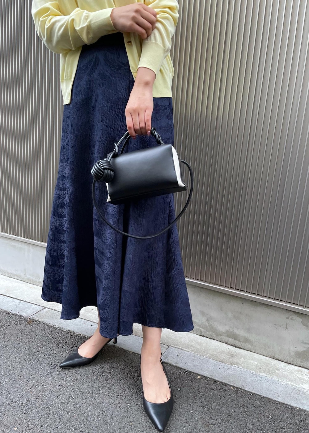 ブラック系のパンプス、イエロー系のカーディガン/ボレロ、イエロー系のニット/セーターを着用したレディースの冬コーディネートの9枚目の写真