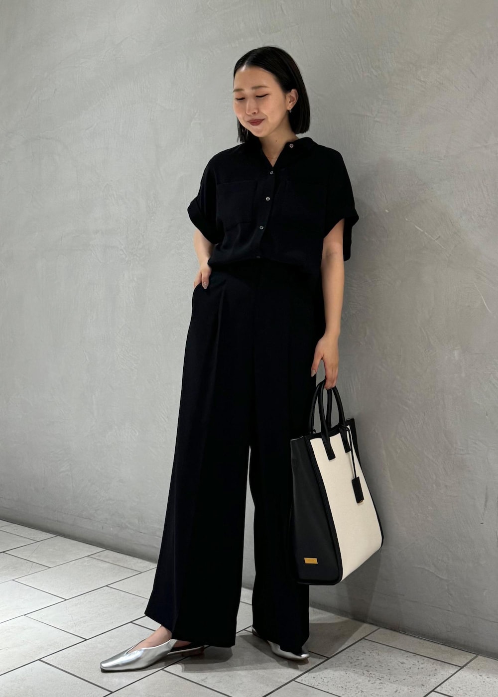 ブラック系のトートバッグ、シルバー系のパンプス、ブラック系のシャツ/ブラウスを着用したレディースの春コーディネートの2枚目の写真