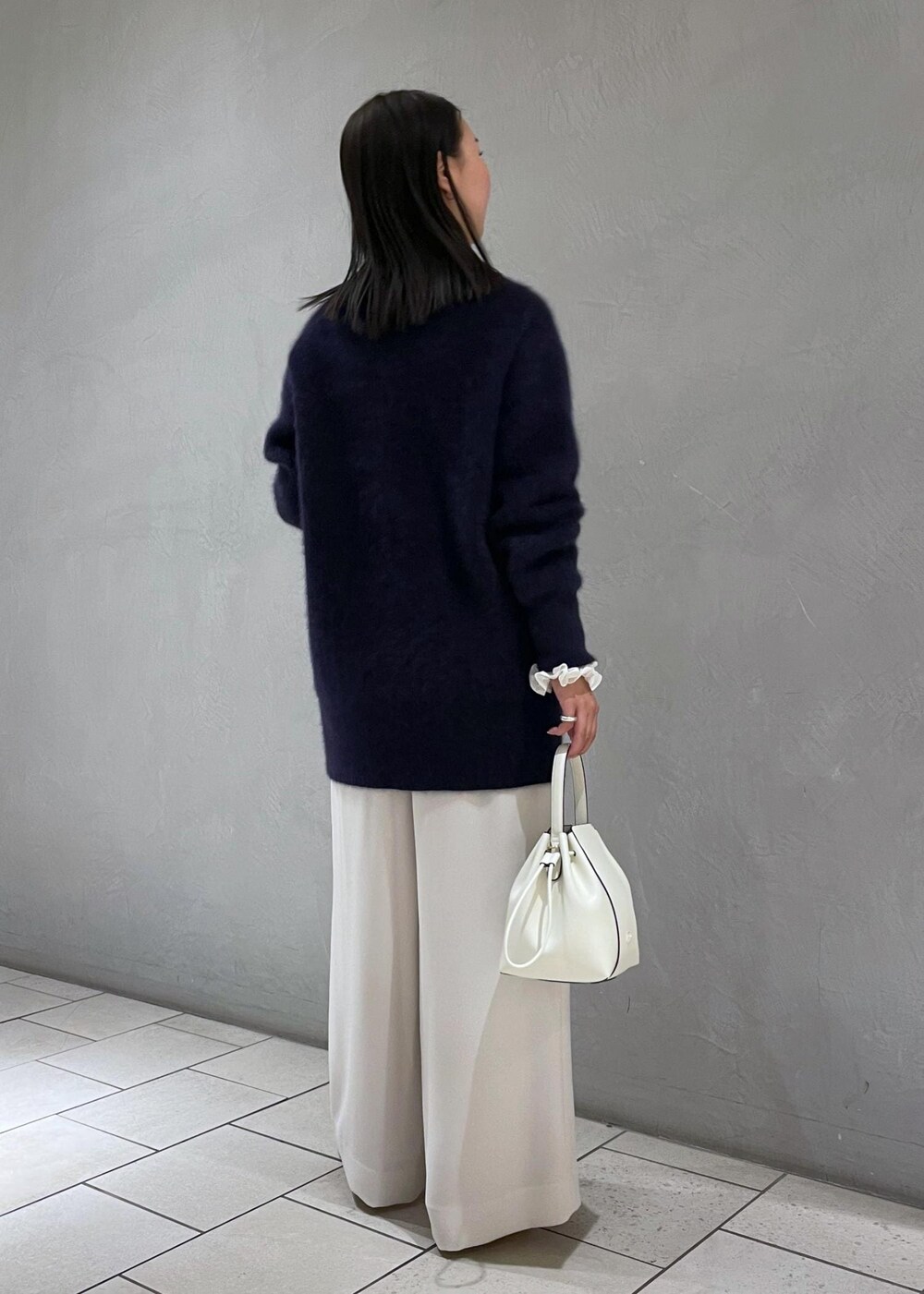 ホワイト系のハンドバッグ、ベージュ系のパンプス、ブルー系のカーディガン/ボレロを着用したレディースの冬コーディネートの5枚目の写真