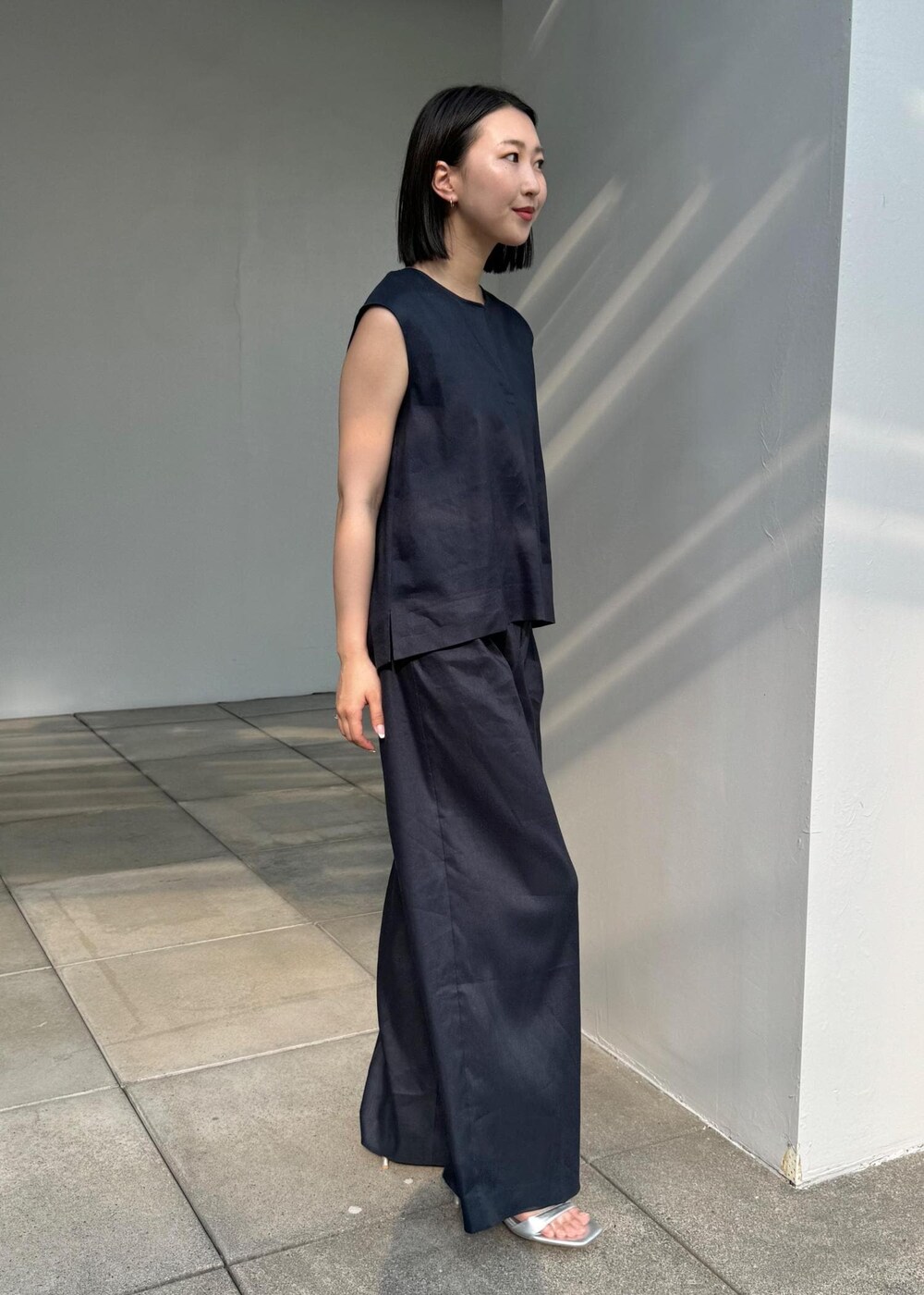 シルバー系のサンダル、シルバー系のハンドバッグ、ブルー系のシャツ/ブラウスを着用したレディースの夏コーディネートの2枚目の写真