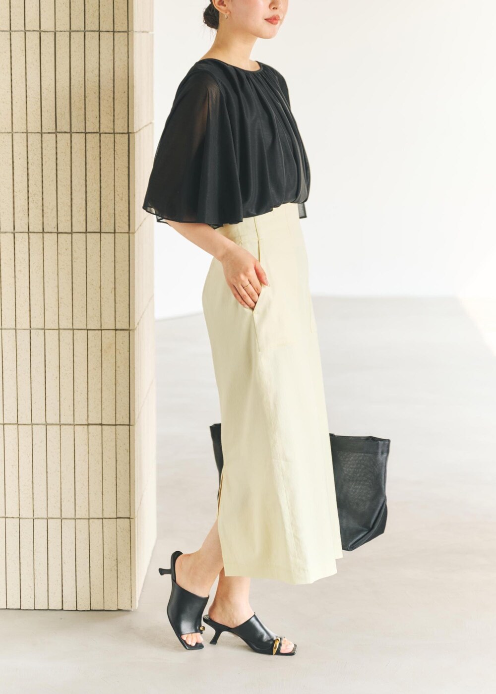 ブラック系のサンダル、ブラック系のトートバッグ、イエロー系のスカートを着用したレディースの春コーディネートの3枚目の写真