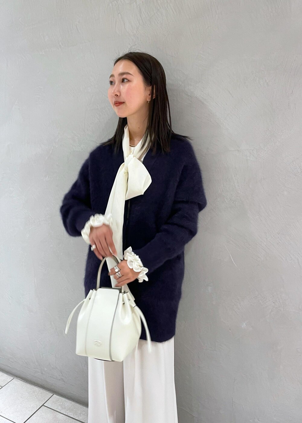ホワイト系のハンドバッグ、ベージュ系のパンプス、ブルー系のカーディガン/ボレロを着用したレディースの冬コーディネートの6枚目の写真