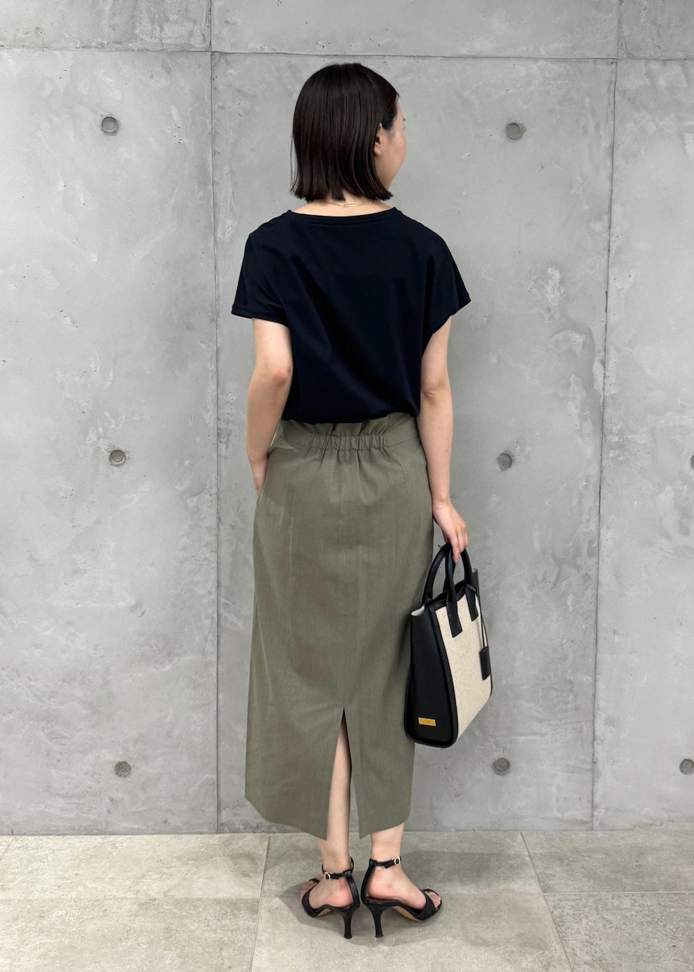 ブラック系のサンダル、グリーン系のスカート、ブラック系のTシャツ/カットソーを着用したレディースの夏コーディネートの3枚目の写真