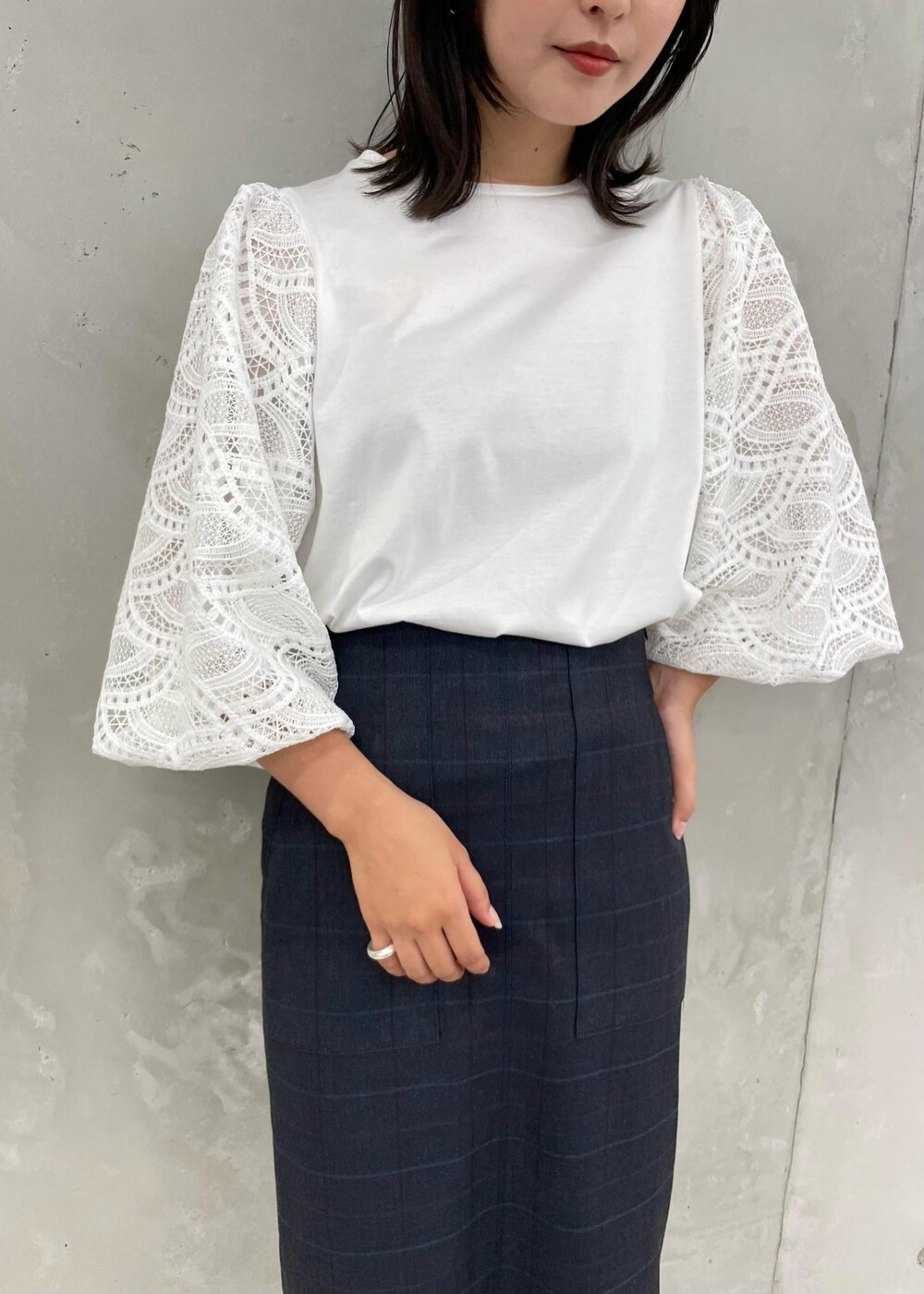 ブラック系のパンプス、グレー系のトートバッグ、ブルー系のスカートを着用したレディースの秋コーディネートの5枚目の写真