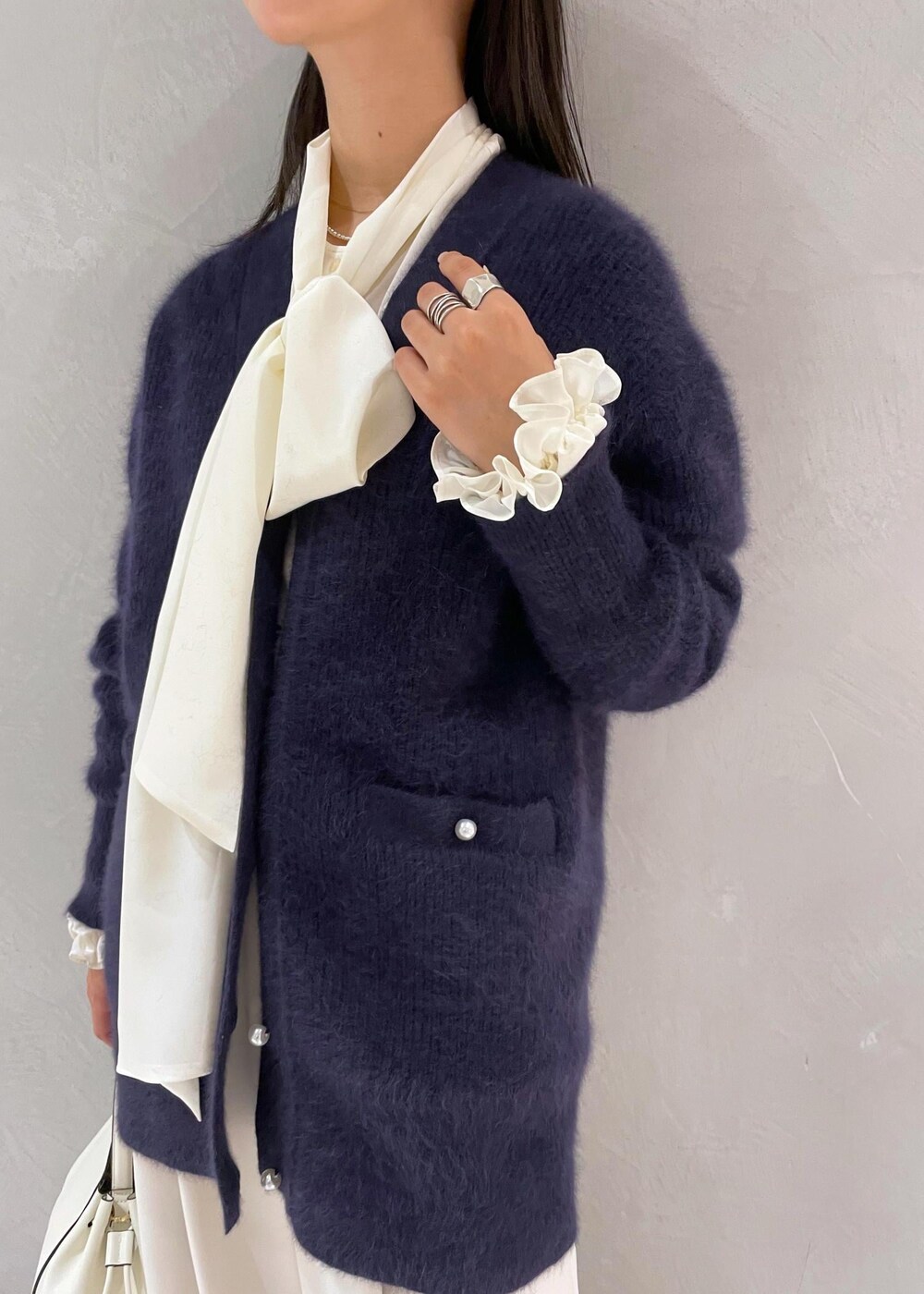 ホワイト系のハンドバッグ、ベージュ系のパンプス、ブルー系のカーディガン/ボレロを着用したレディースの冬コーディネートの8枚目の写真