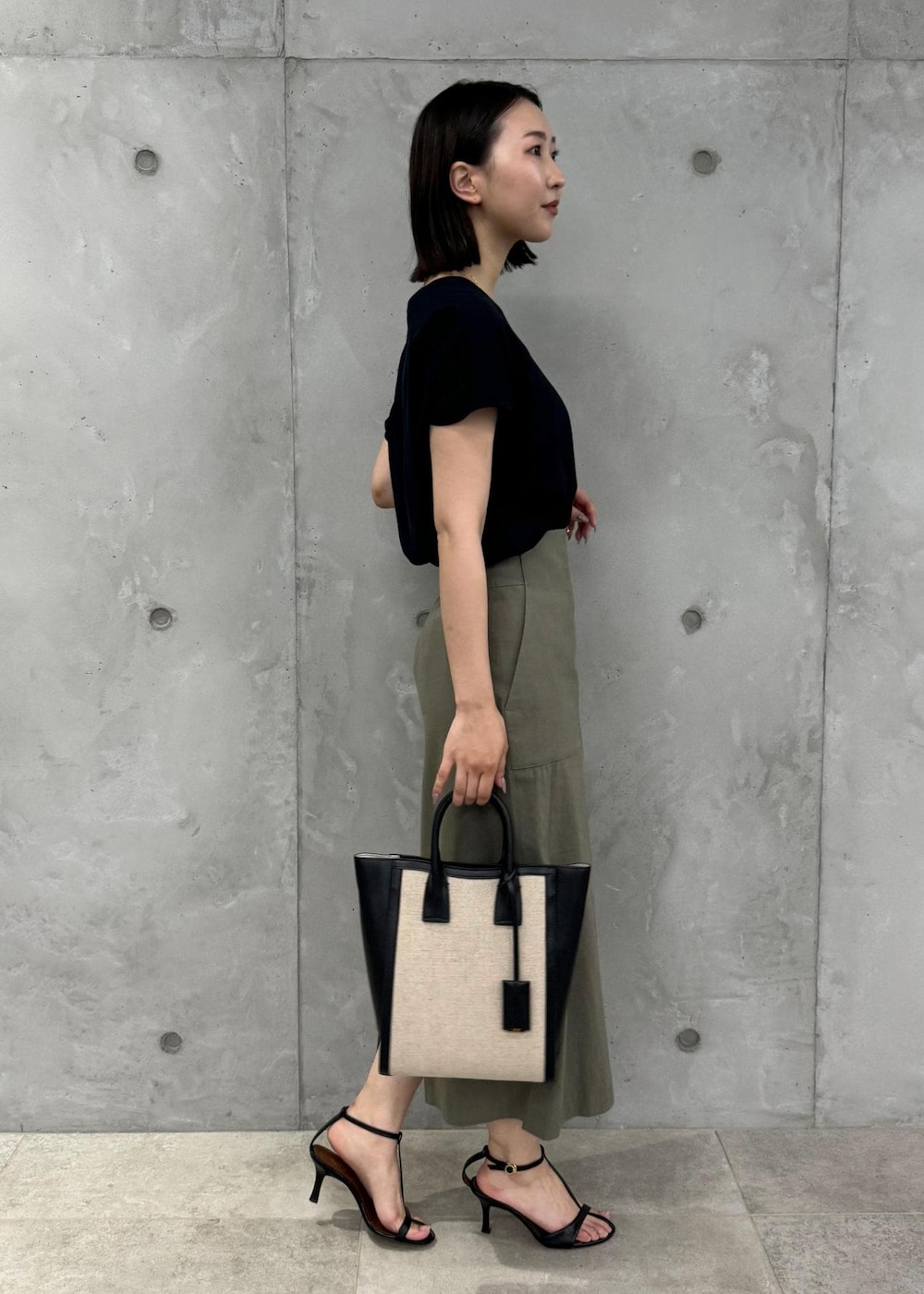 ブラック系のサンダル、グリーン系のスカート、ブラック系のTシャツ/カットソーを着用したレディースの夏コーディネートの2枚目の写真