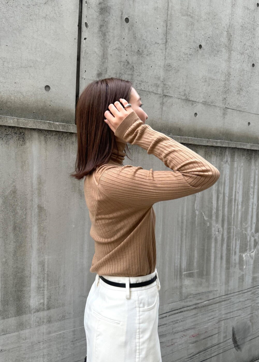 ブラウン系のパンプス、ブラック系のハンドバッグ、ホワイト系のスカートを着用したレディースの冬コーディネートの7枚目の写真