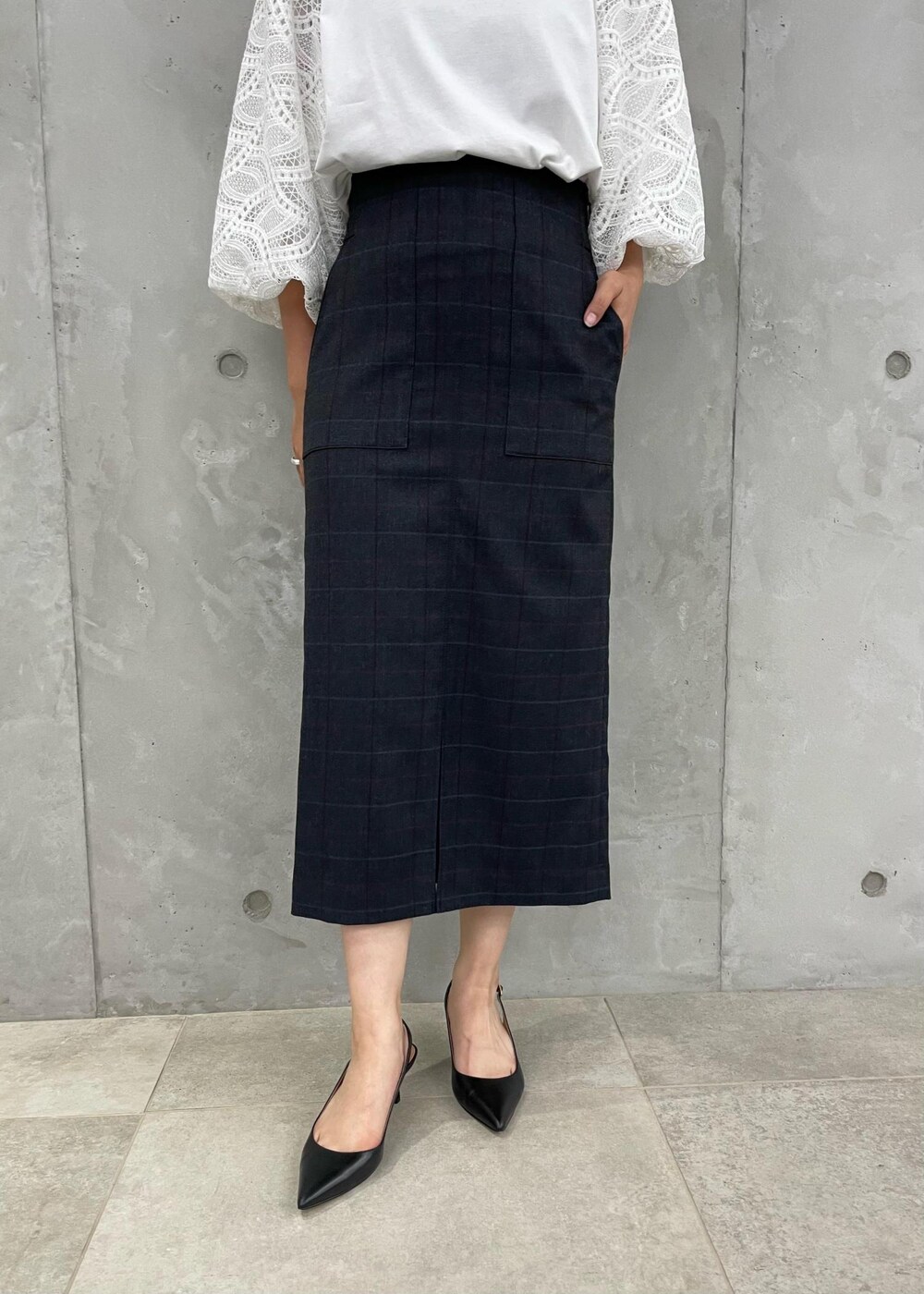 ブラック系のパンプス、グレー系のトートバッグ、ブルー系のスカートを着用したレディースの秋コーディネートの7枚目の写真