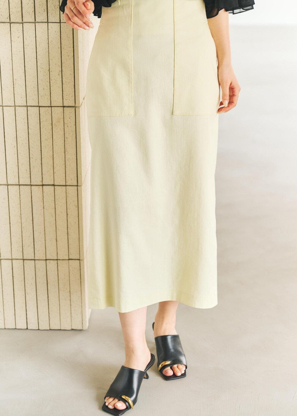 ブラック系のサンダル、ブラック系のトートバッグ、イエロー系のスカートを着用したレディースの春コーディネートの6枚目の写真