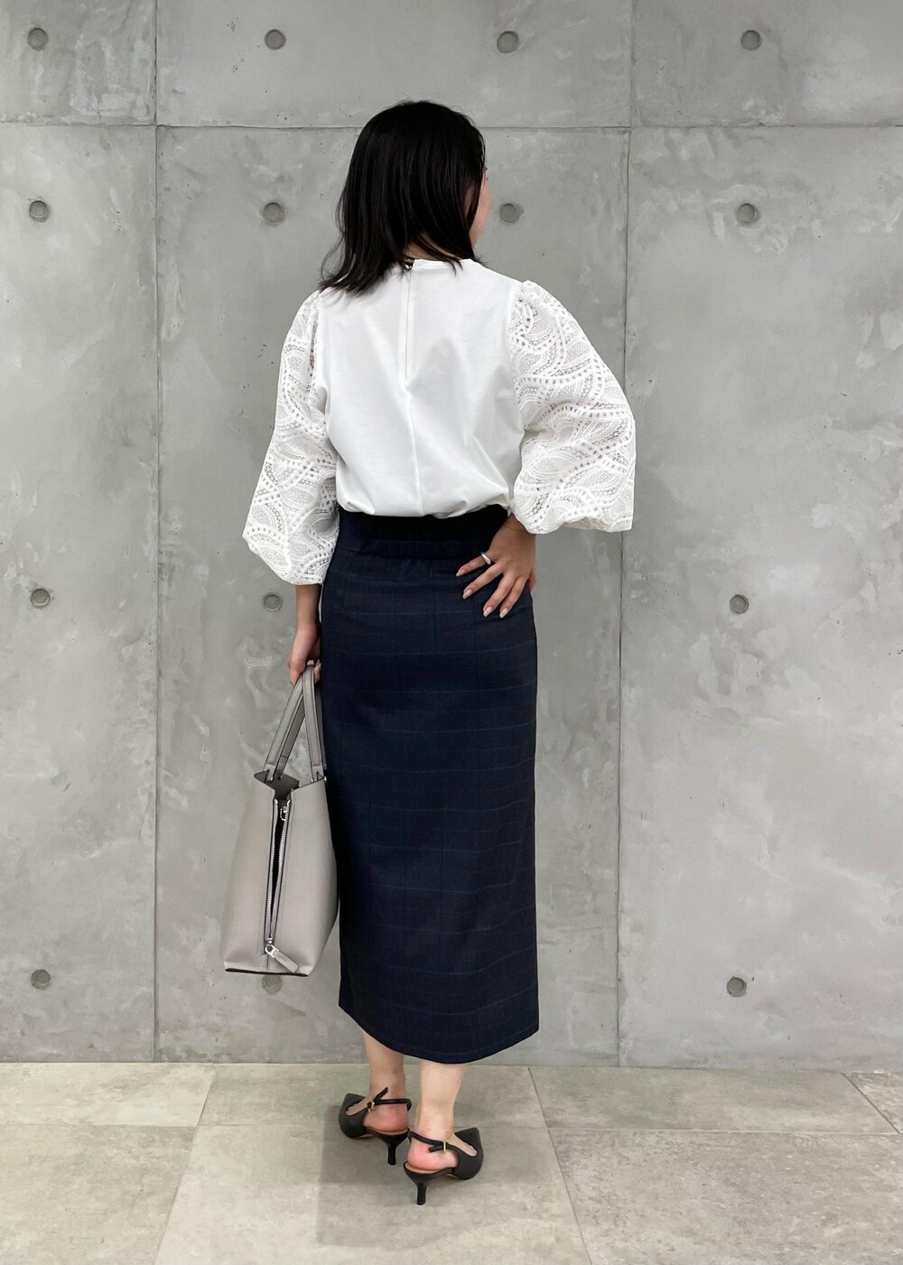 ブラック系のパンプス、グレー系のトートバッグ、ブルー系のスカートを着用したレディースの秋コーディネートの3枚目の写真