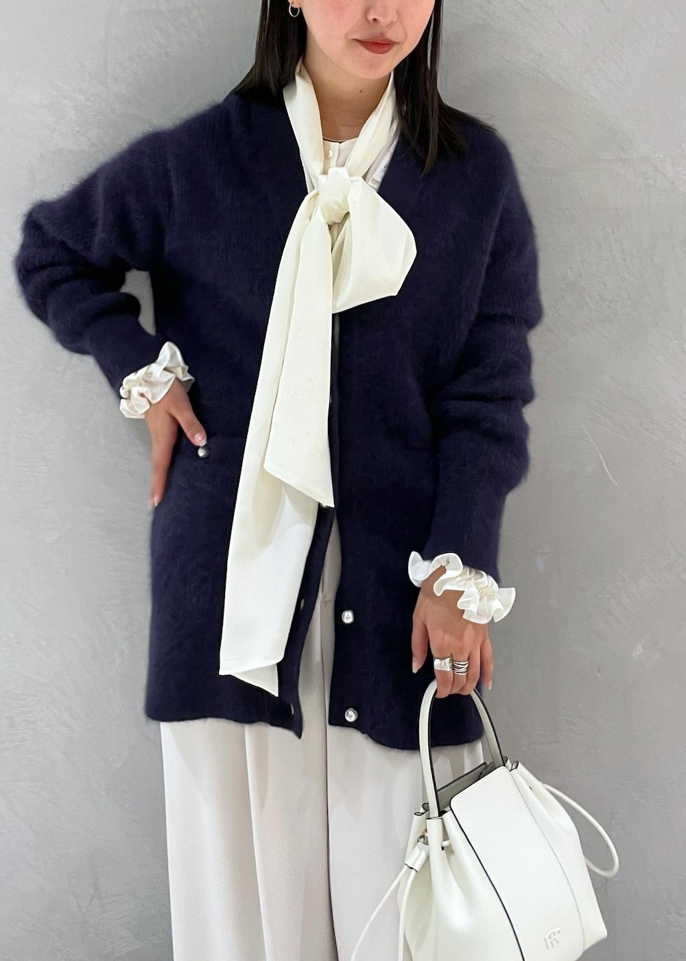 ホワイト系のハンドバッグ、ベージュ系のパンプス、ブルー系のカーディガン/ボレロを着用したレディースの冬コーディネートの7枚目の写真
