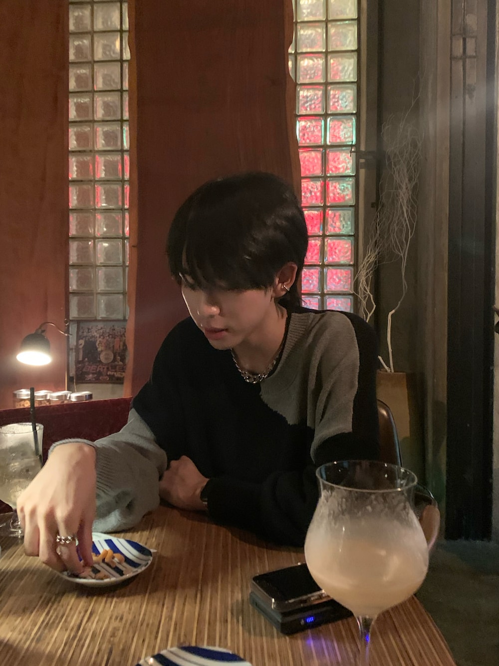 ブラック系のニット/セーター、ブラック系のデニムパンツ、ホワイト系のスニーカーを着用したメンズの秋コーディネートの2枚目の写真