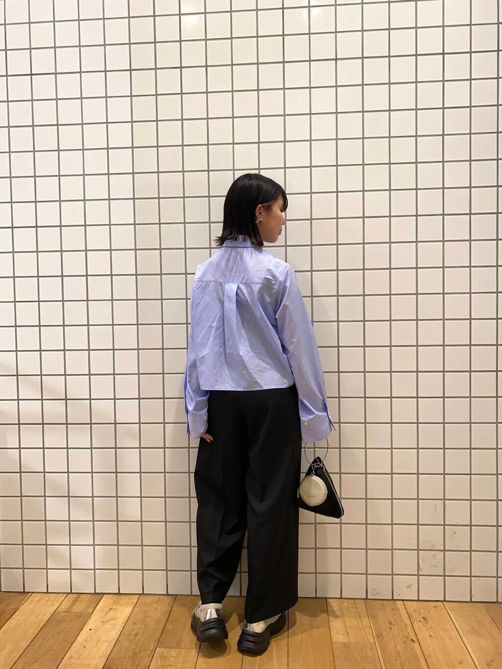 グレー系のスニーカー、ブラック系のハンドバッグ、ブルー系のシャツ/ブラウスを着用したレディースの春コーディネートの2枚目の写真