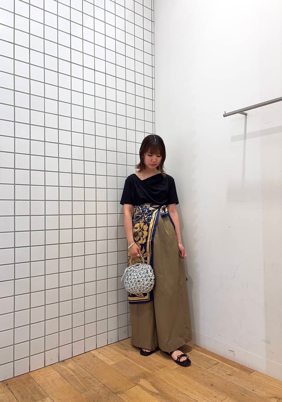 シルバー系のハンドバッグ、ベージュ系のその他パンツ、ブラック系のTシャツ/カットソーを着用したレディースの夏コーディネートの2枚目の写真