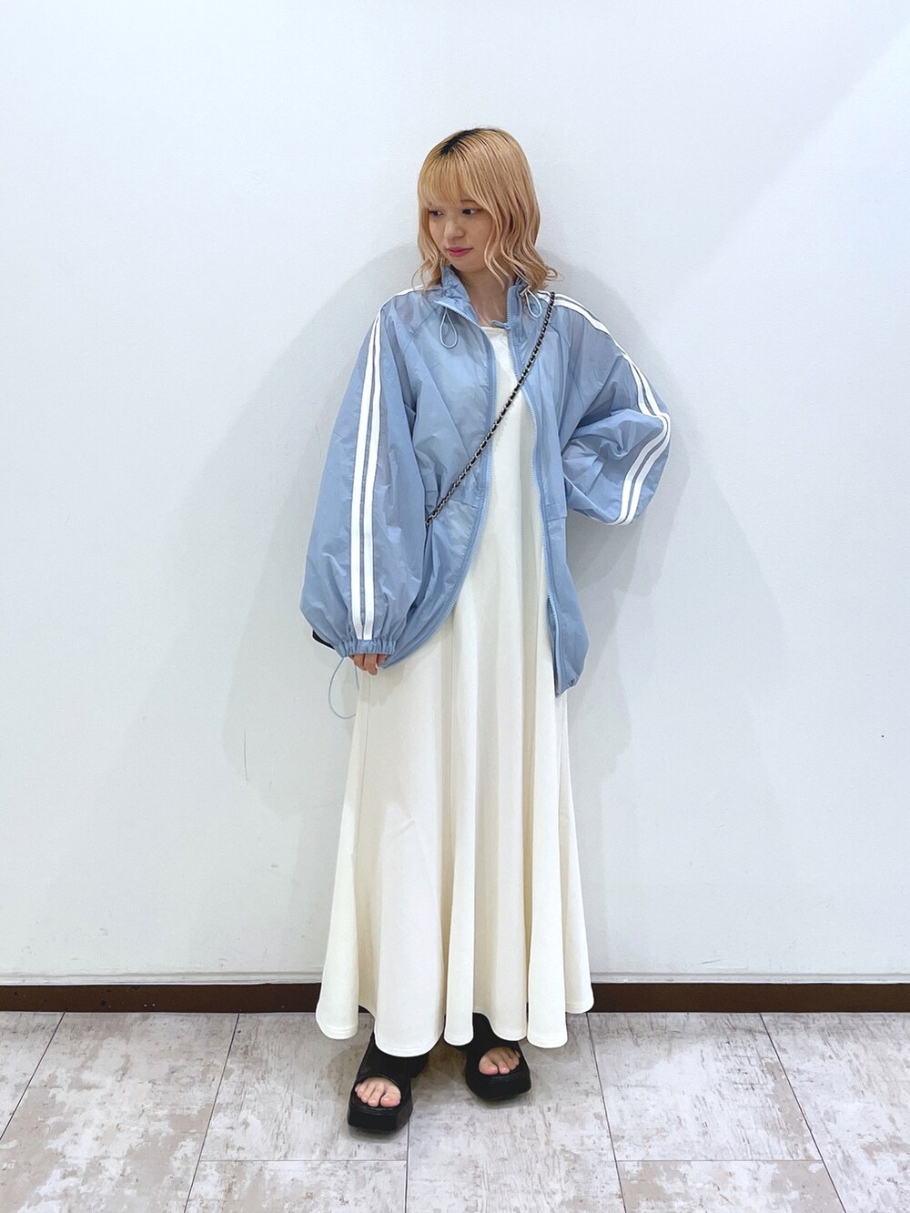 ブルー系のブルゾン、ホワイト系のワンピース、ブラック系のサンダルを着用したレディースの春コーディネートの2枚目の写真