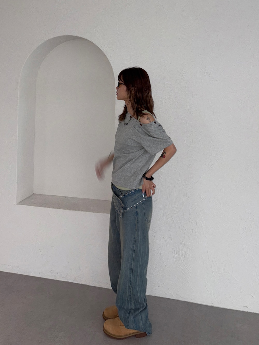 ブルー系のデニムパンツ、グレー系のTシャツ/カットソー、イエロー系のブーツを着用したレディースの夏コーディネートの2枚目の写真