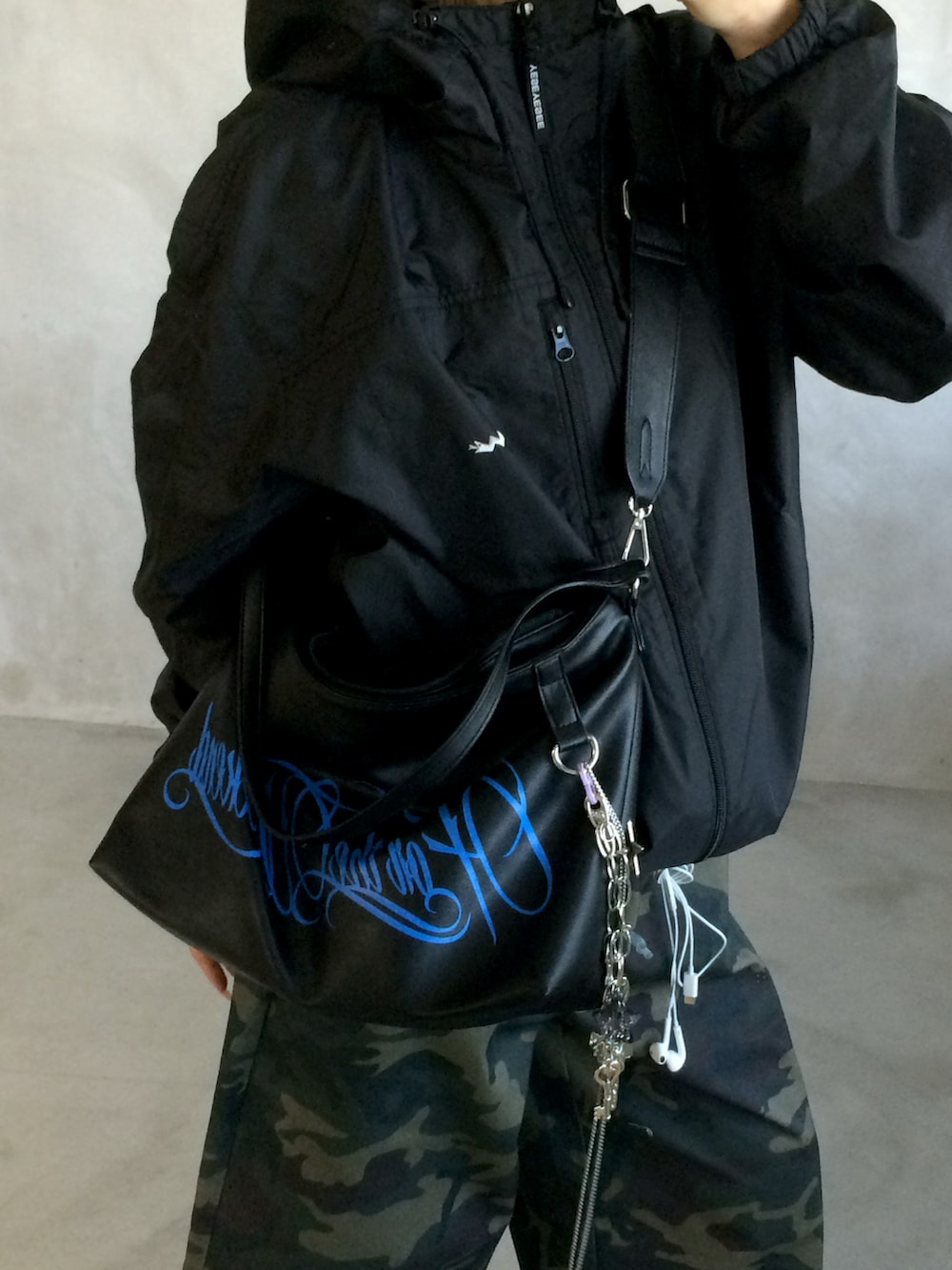 ブラック系のジャケット/アウター、グリーン系のパンツ、ブラック系のショルダーバッグを着用したレディースの春コーディネートの2枚目の写真