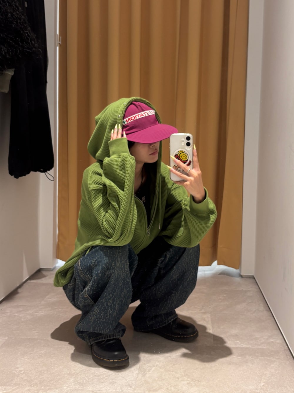 グリーン系のパーカー、ブラック系のボストンバッグ、ブルー系のデニムパンツを着用したレディースの秋コーディネートの2枚目の写真