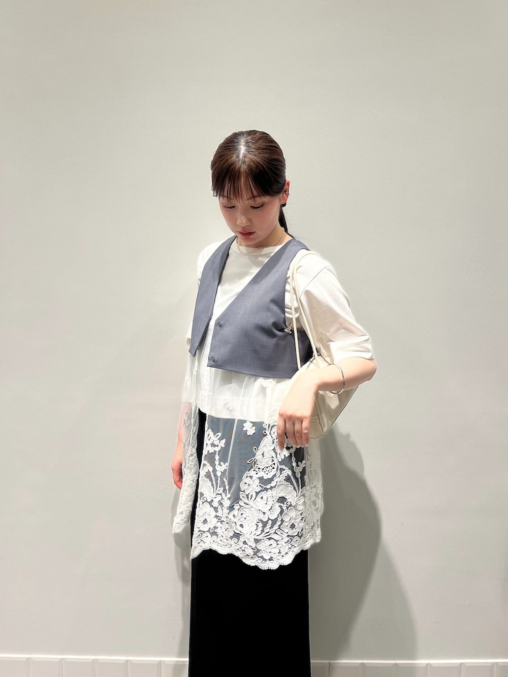 グレー系のベスト、ブラック系のスカート、ホワイト系のTシャツ/カットソーを着用したレディースの夏コーディネートの3枚目の写真