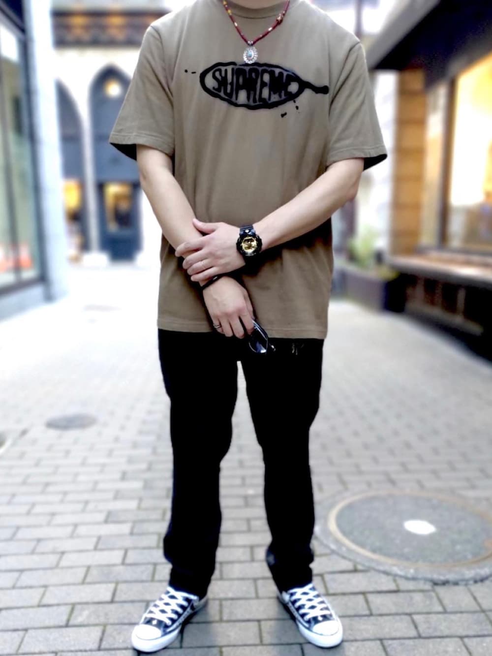 ブラウン系のTシャツ/カットソー、ブラック系のチノパンツ、ブラック系のスニーカーを着用したメンズの秋コーディネートの2枚目の写真