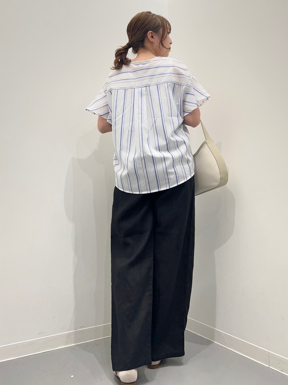 ブルー系のシャツ/ブラウス、ブラック系のその他パンツ、ベージュ系のハンドバッグを着用したレディースの春コーディネートの6枚目の写真