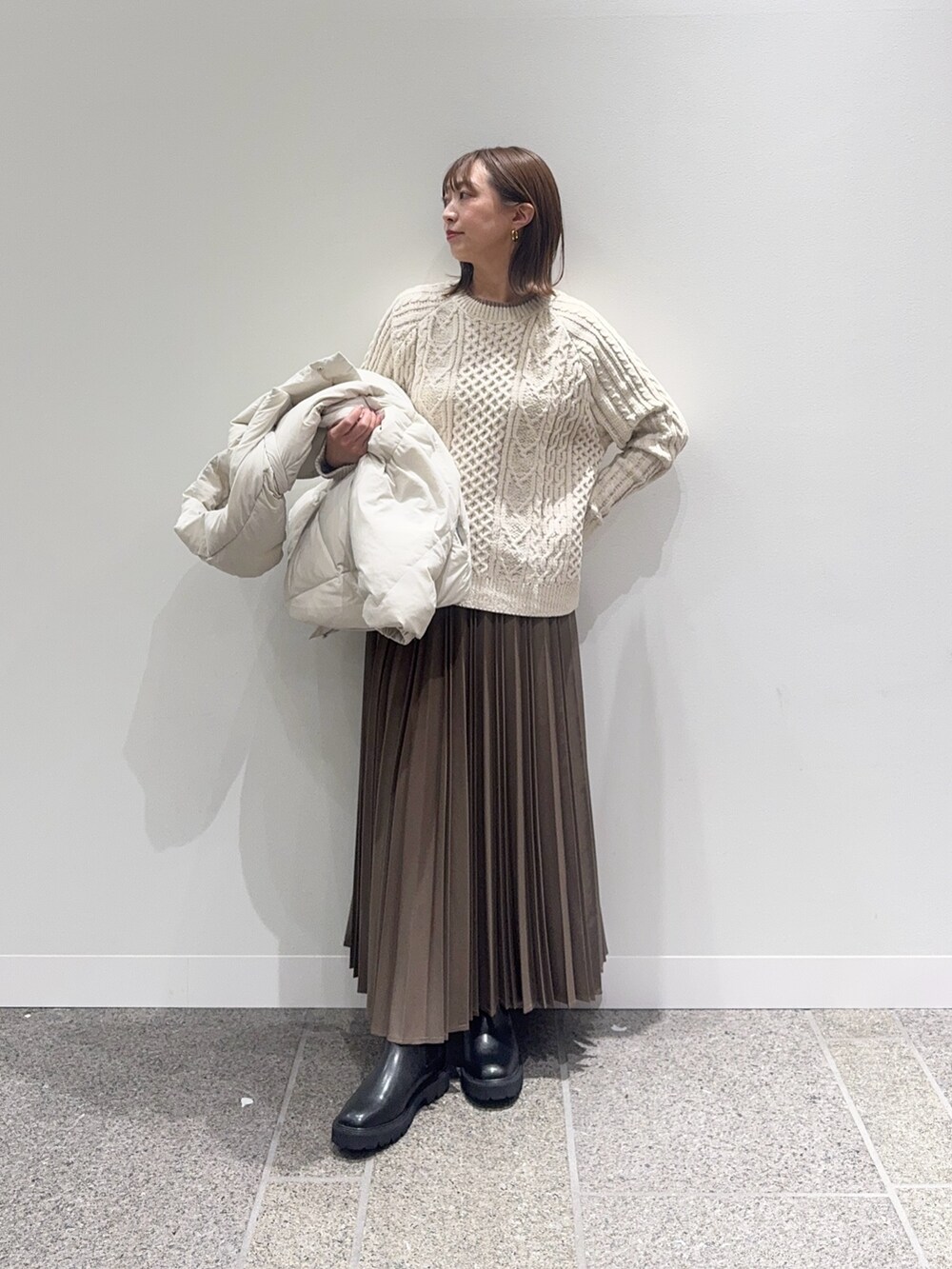 ホワイト系のダウンジャケット/コート、ホワイト系のニット/セーター、ベージュ系のスカートを着用したレディースの冬コーディネートの6枚目の写真