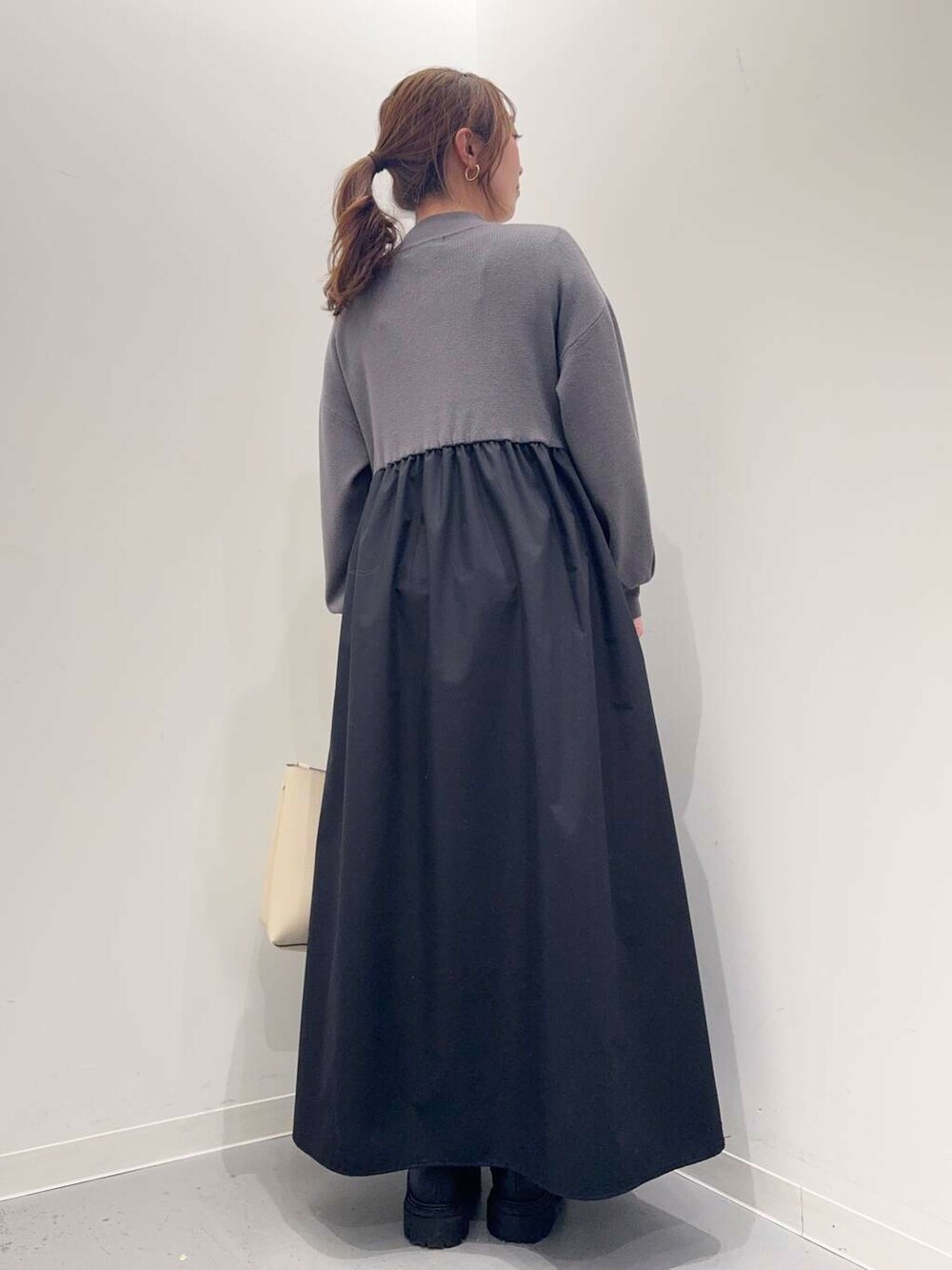 ブラック系のブーツ、ホワイト系のトートバッグ、グレー系のワンピースを着用したレディースの冬コーディネートの3枚目の写真