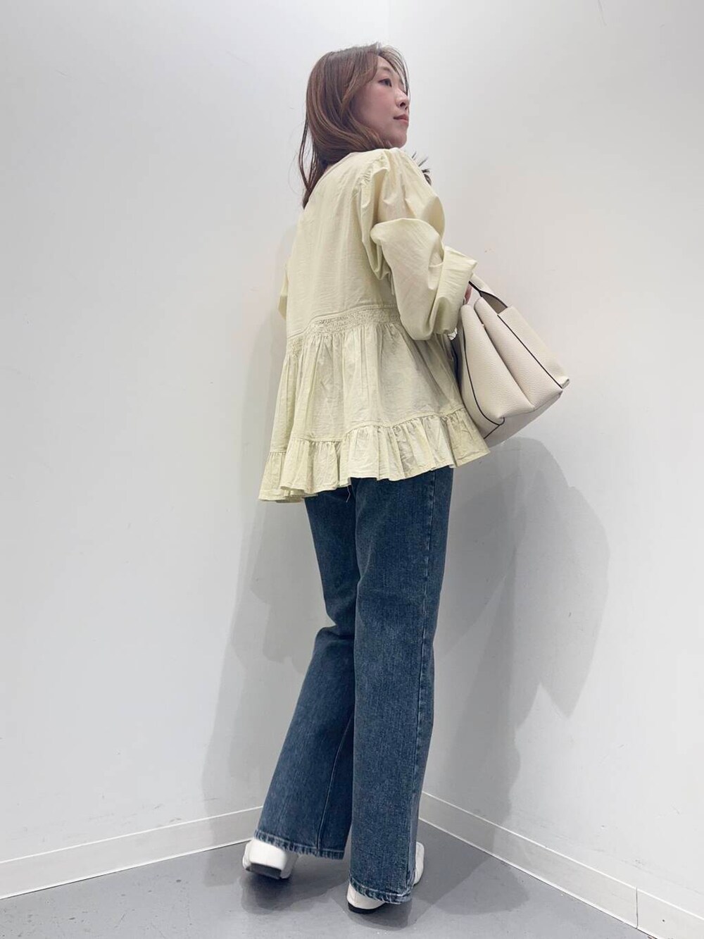 ホワイト系のトートバッグ、ブルー系のデニムパンツ、ホワイト系のローファーを着用したレディースの春コーディネートの5枚目の写真