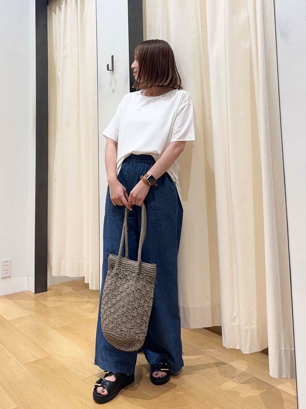 グレー系のトートバッグ、ブルー系のデニムパンツ、ブラック系のサンダルを着用したレディースの夏コーディネートの4枚目の写真