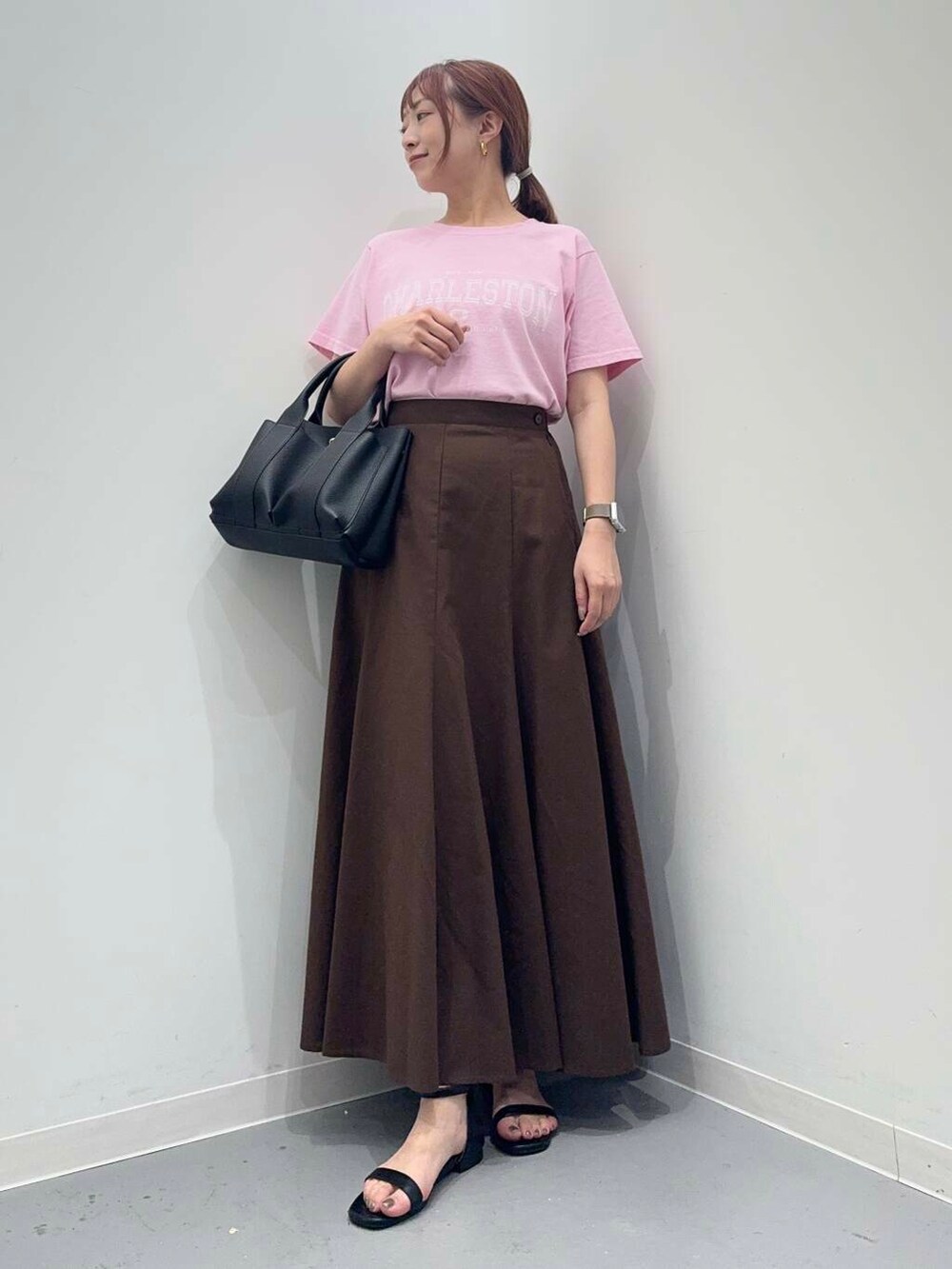 ブラック系のトートバッグ、ブラック系のサンダル、ブラウン系のスカートを着用したレディースの夏コーディネートの2枚目の写真