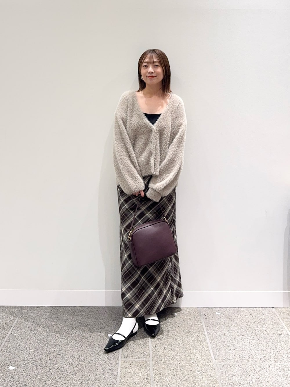 ベージュ系のカーディガン/ボレロ、ブラウン系のスカート、レッド系のショルダーバッグを着用したレディースの秋コーディネートの4枚目の写真