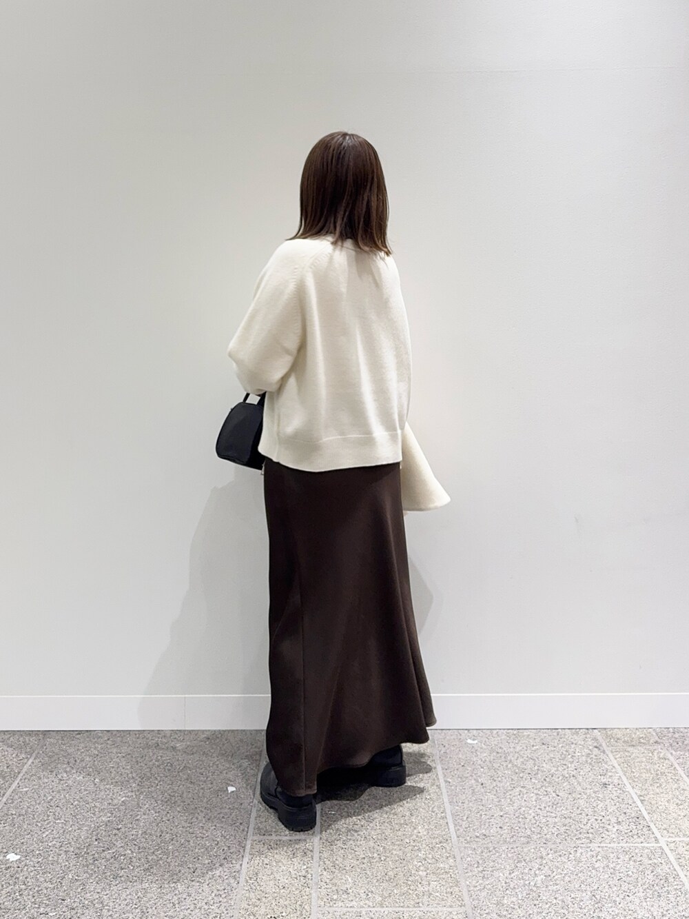 ホワイト系のピーコート、ホワイト系のニット/セーター、ブラック系のボストンバッグを着用したレディースの冬コーディネートの6枚目の写真