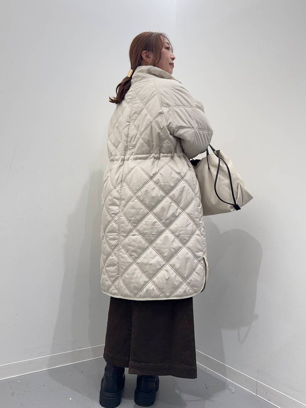 ホワイト系のショルダーバッグ、ブラック系のブーツ、ベージュ系のその他アウターを着用したレディースの冬コーディネートの7枚目の写真