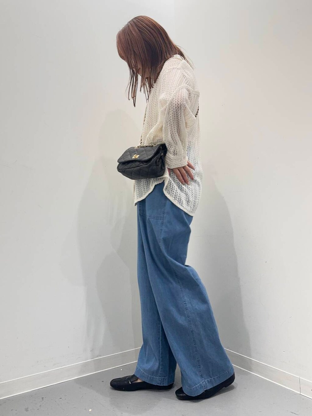 ブラック系のローファー、ブルー系のデニムパンツ、ブラウン系のショルダーバッグを着用したレディースの夏コーディネートの2枚目の写真