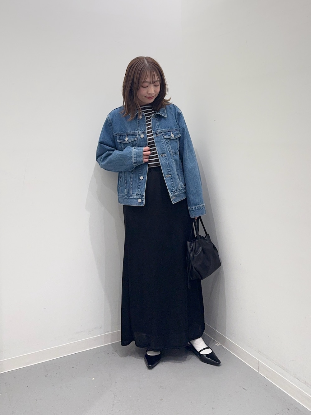 ブルー系のデニムジャケット、ブルー系のTシャツ/カットソー、ブラック系のスカートを着用したレディースの冬コーディネートの4枚目の写真