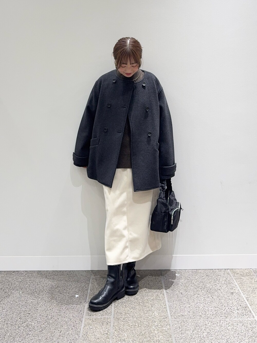 グレー系のピーコート、ブラウン系のニット/セーター、ホワイト系のスカートを着用したレディースの冬コーディネートの5枚目の写真