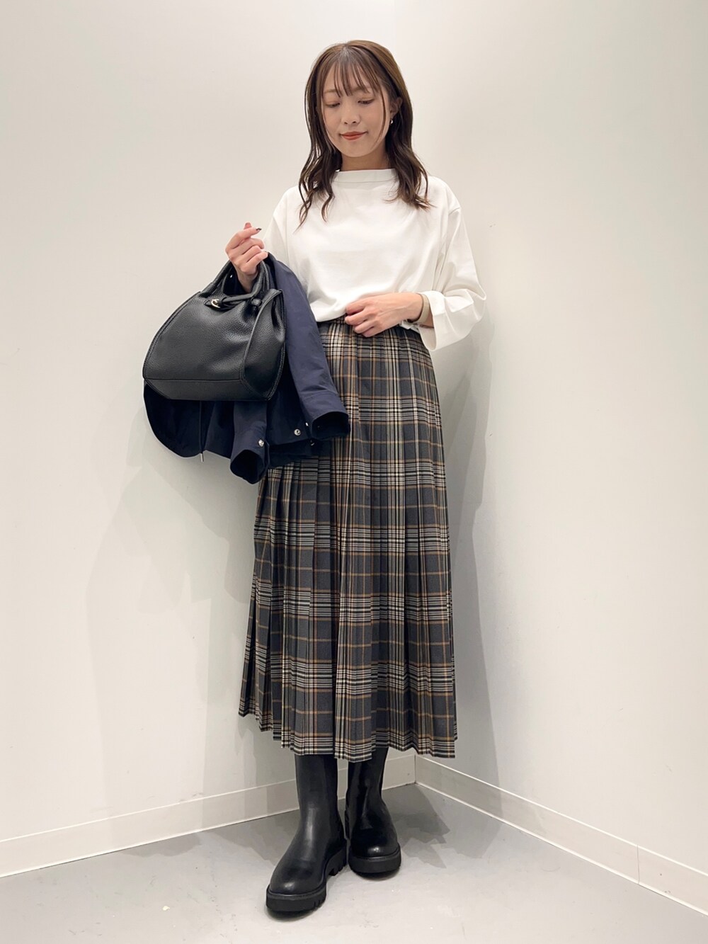 ホワイト系のTシャツ/カットソー、グレー系のスカート、ブルー系のダウンベストを着用したレディースの秋コーディネートの2枚目の写真